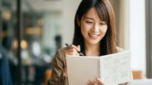 カフェで自分に合う副業を選ぶコツをメモする日本人の女性